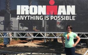 Dr. Draper standing in front of the Ironman "Anything Is Possible" sign, smiling with hands on hips