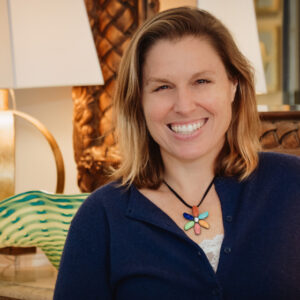 Dr. Emily Stone MD FACOG MSCP smiling wearing a navy blue top and colorful necklace