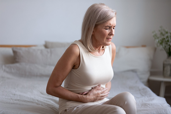 Older woman grimacing in pain holding her abdomen