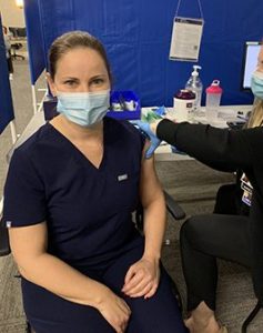 Dr. Vaughan smiling under her mask while getting her COVID-19 vaccination
