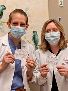 Dr. Hartle and nurse Jeannette showing their COVID-vaccination cards