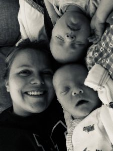 Woman smiling lying down with twin babies