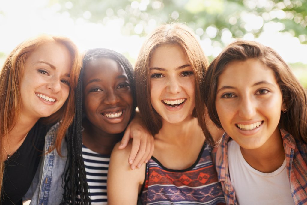 Teen girls smiling and wondering what age should girls go to the gynecologist for the first time