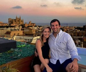 Dr. Caitlin Morin and her fiance sitting in front of the Spain skyline and smiling