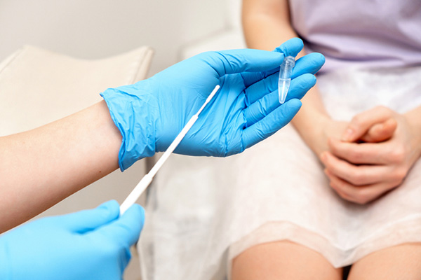 A gynecologist shows a patient the tools she will be using to take a sample during a pelvic exam.