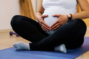 pregnant woman doing pelvic floor physical therapy sitting on yoga mat