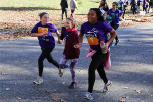 Girls on the run running outside in purple shirts and running shoes