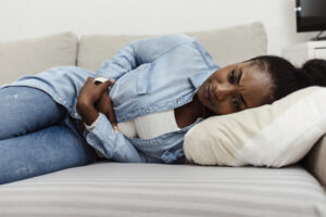 woman on couch suffering in need of uterine fibroids treatment