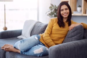 woman sitting on a couch smiling while doing pelvic floor exercises