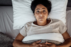 Middle aged woman lying in bed with menopause symptoms insomnia and hot flashes