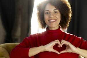 A smiling woman forms a heart shape with her hands for heart health