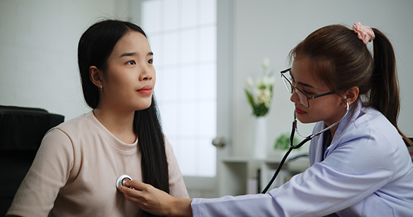 A physician checks a female patient’s heart rate during a well-woman visit