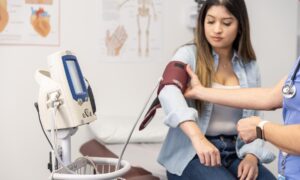 A doctor monitors a female patient's blood pressure at a medical appointment.