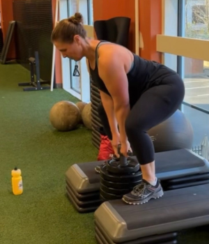 Dr. Emily Stone squatting on risers and lifting a heavy weight