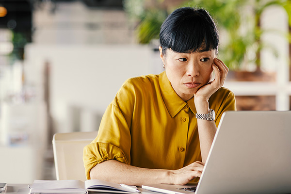 A middle aged businesswoman experiences perimenopause brain fog on computer at work
